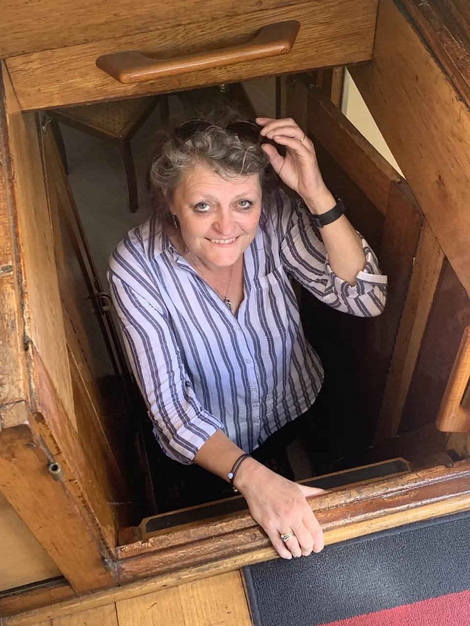 Kaz glimlacht terwijl ze door een houten luik aan boord van Maria omhoogkomt