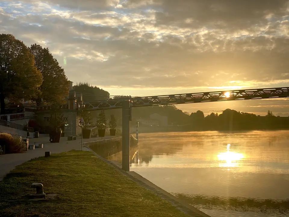 Gouden avondlicht over een rivier en voetbrug
