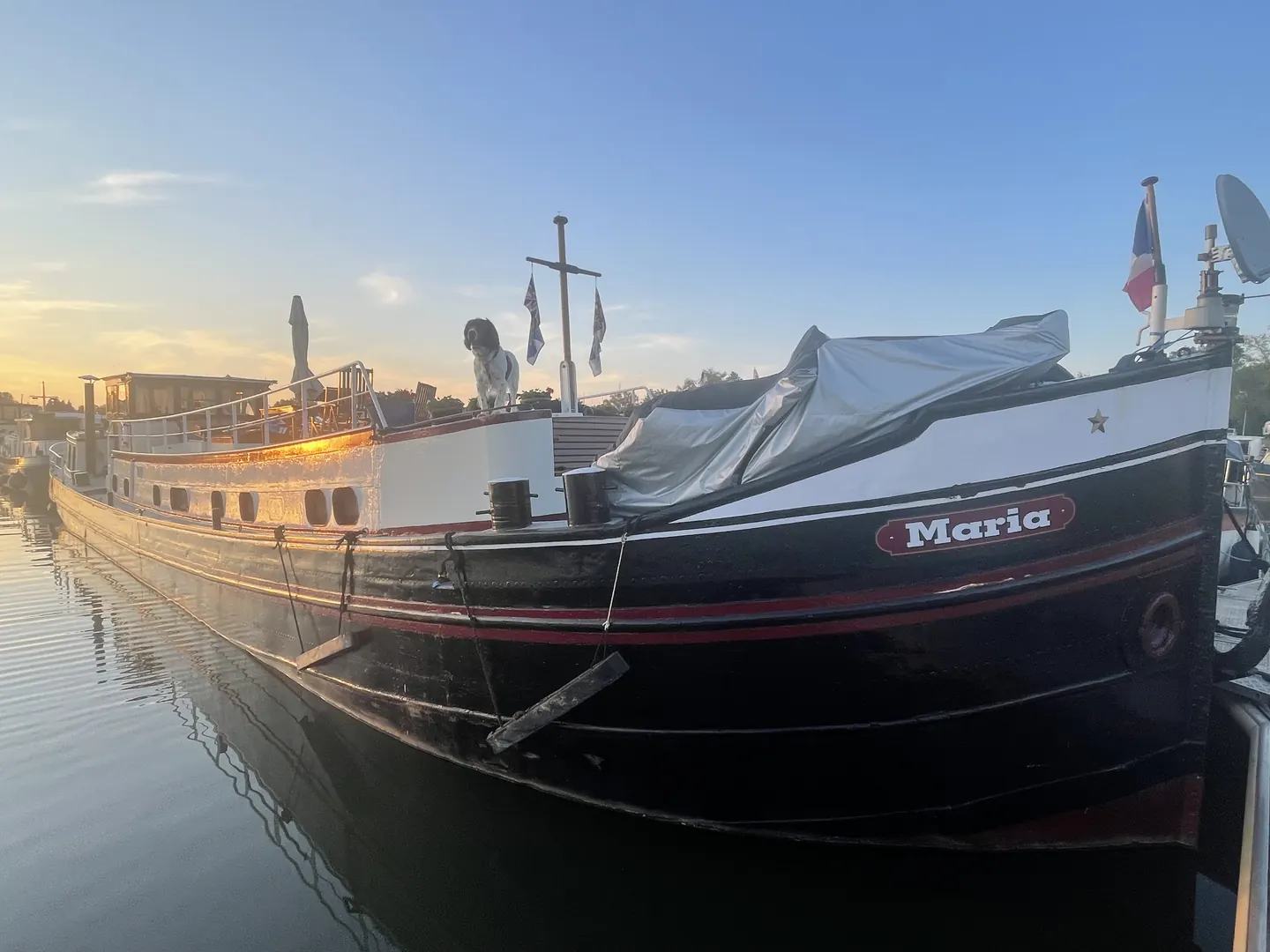 Oscar standing on Maria's deck as the evening sun lights the historic barge
