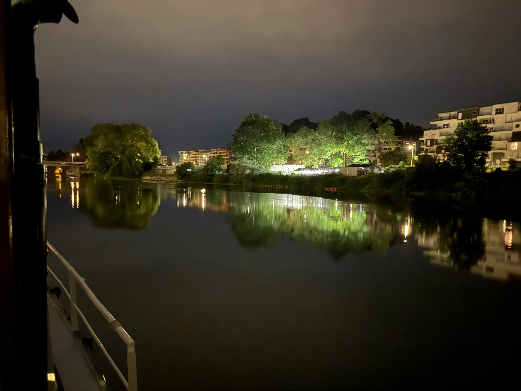 Les lumières de Besançon se reflètent dans l’eau, vues au-delà du bastingage de Maria, de nuit