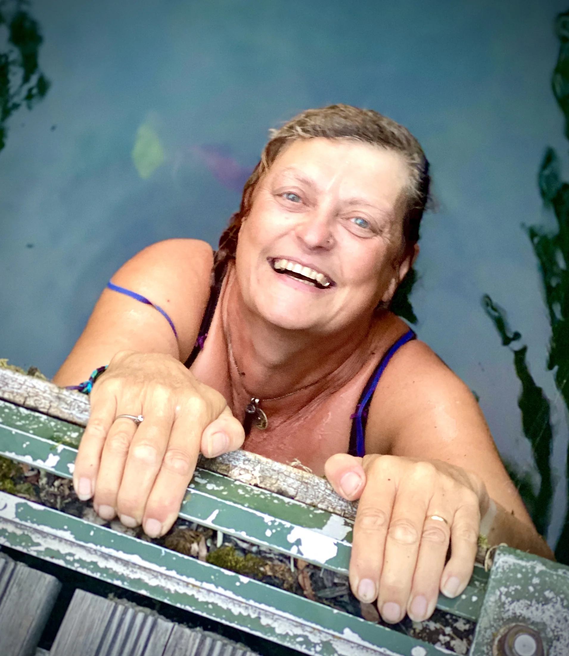 Een lachende zwemmer houdt de ladder naast Maria vast na wat verkoeling in het water