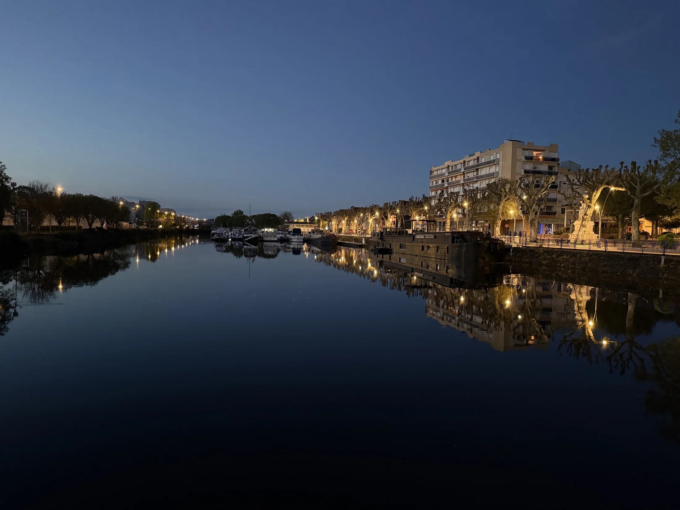 Lichten weerspiegeld in het stille water van een haven bij nacht