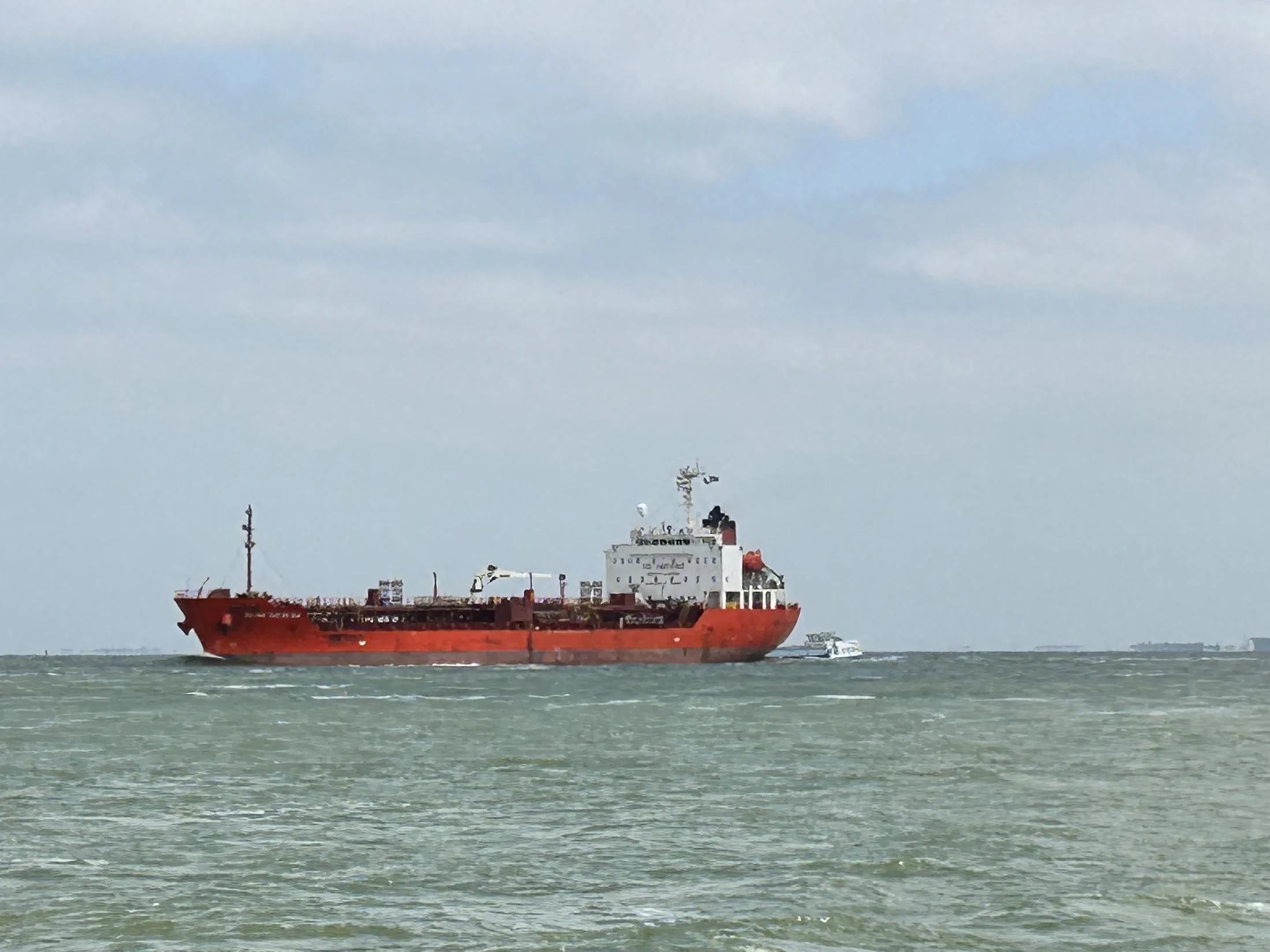 Een groot rood vrachtschip onderweg op de open vaarweg voor de beroepsvaart