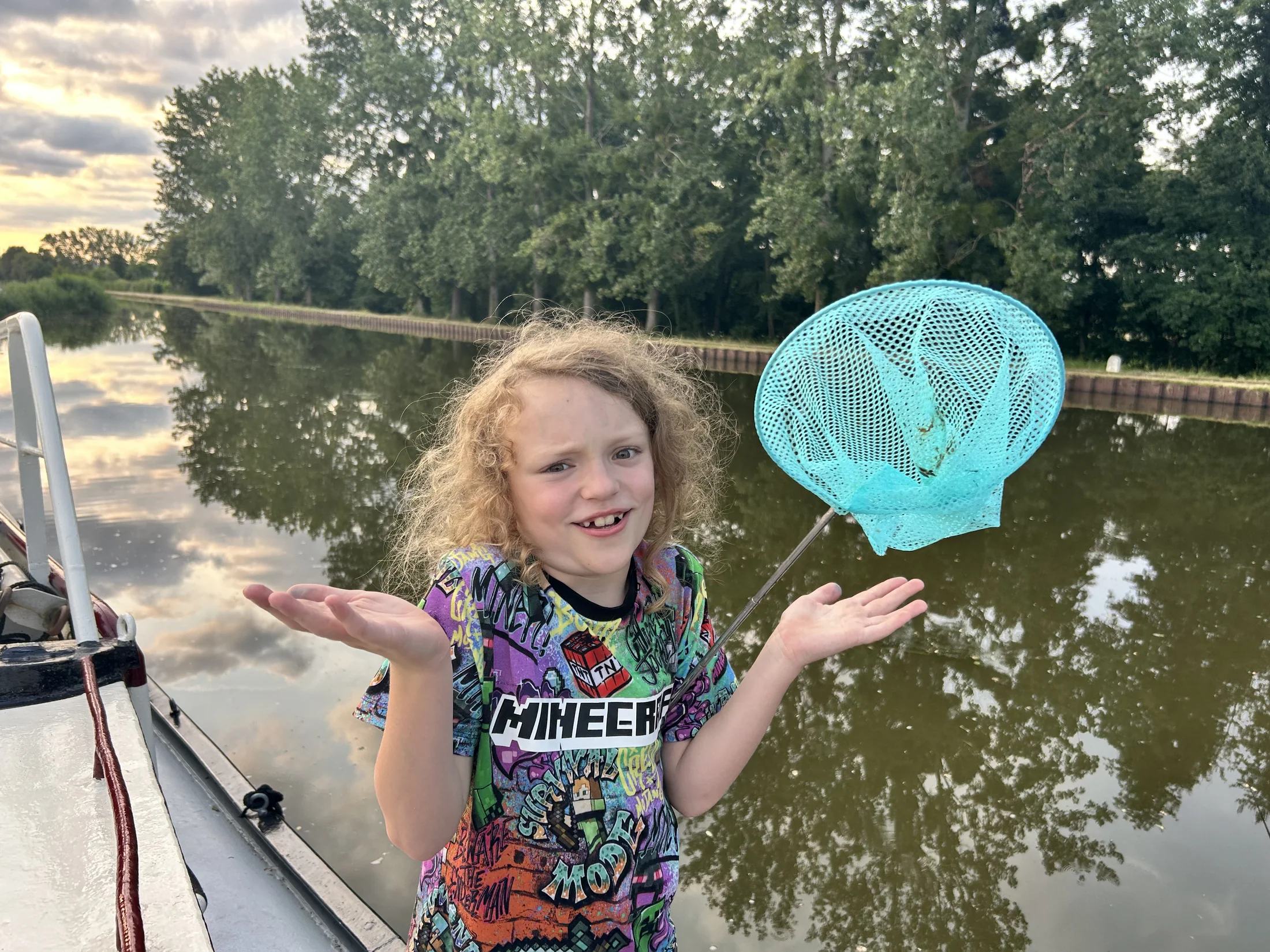 Harry houdt een visnet vast en haalt zijn schouders op naast het kanaal, aan boord van Maria