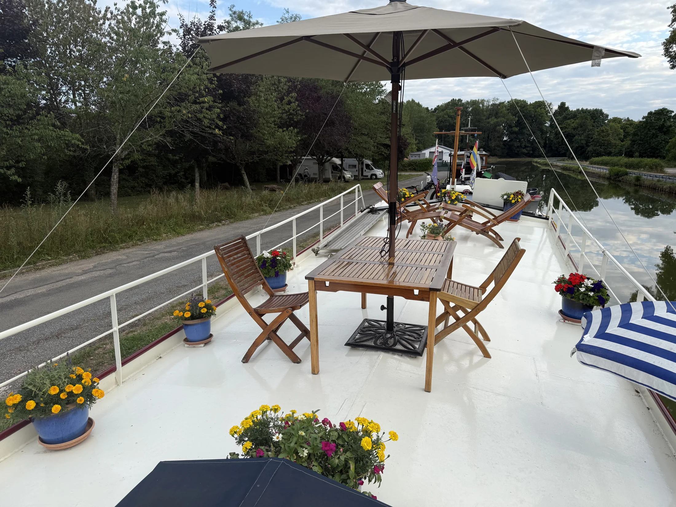 Maria’s dek ingericht met tafels en stoelen, omringd door bloeiende planten