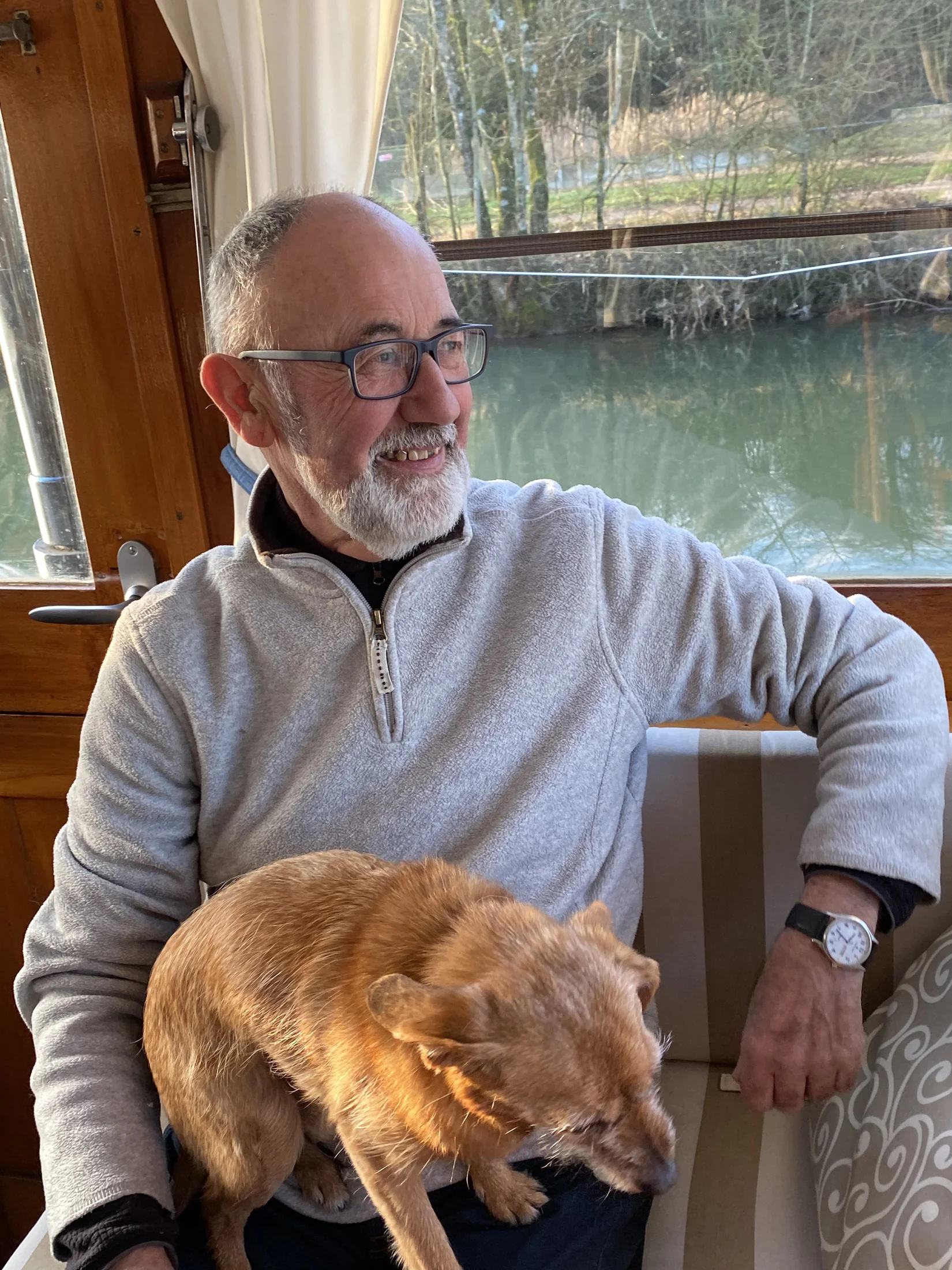 Roy aan boord van Maria, met zijn hond Splif op schoot