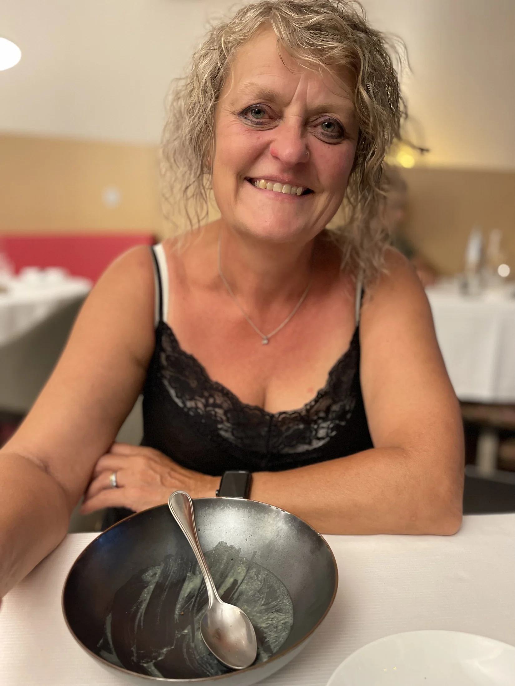 Kaz sourit à la table du restaurant, son bol vide et sa cuillère devant elle