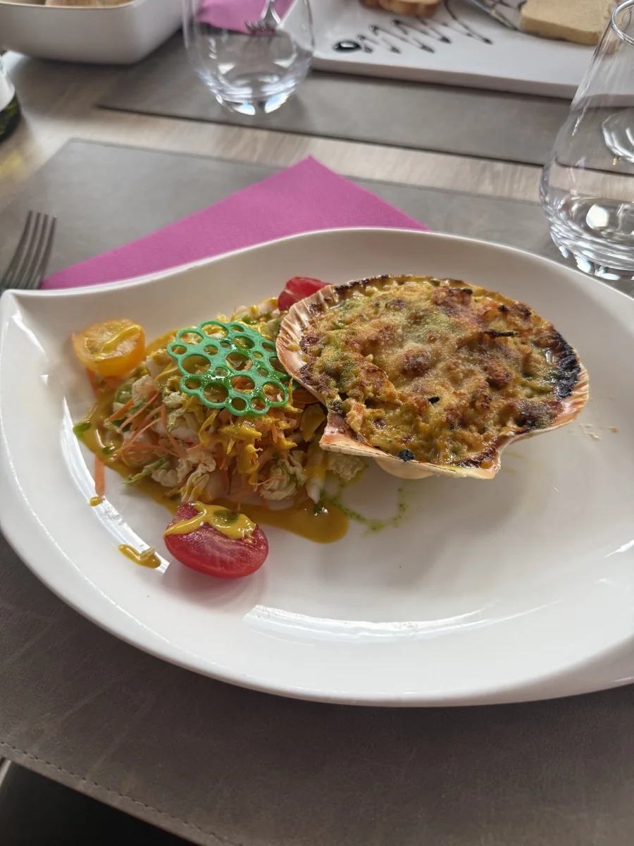 Un plat servi dans une coquille Saint-Jacques avec des légumes