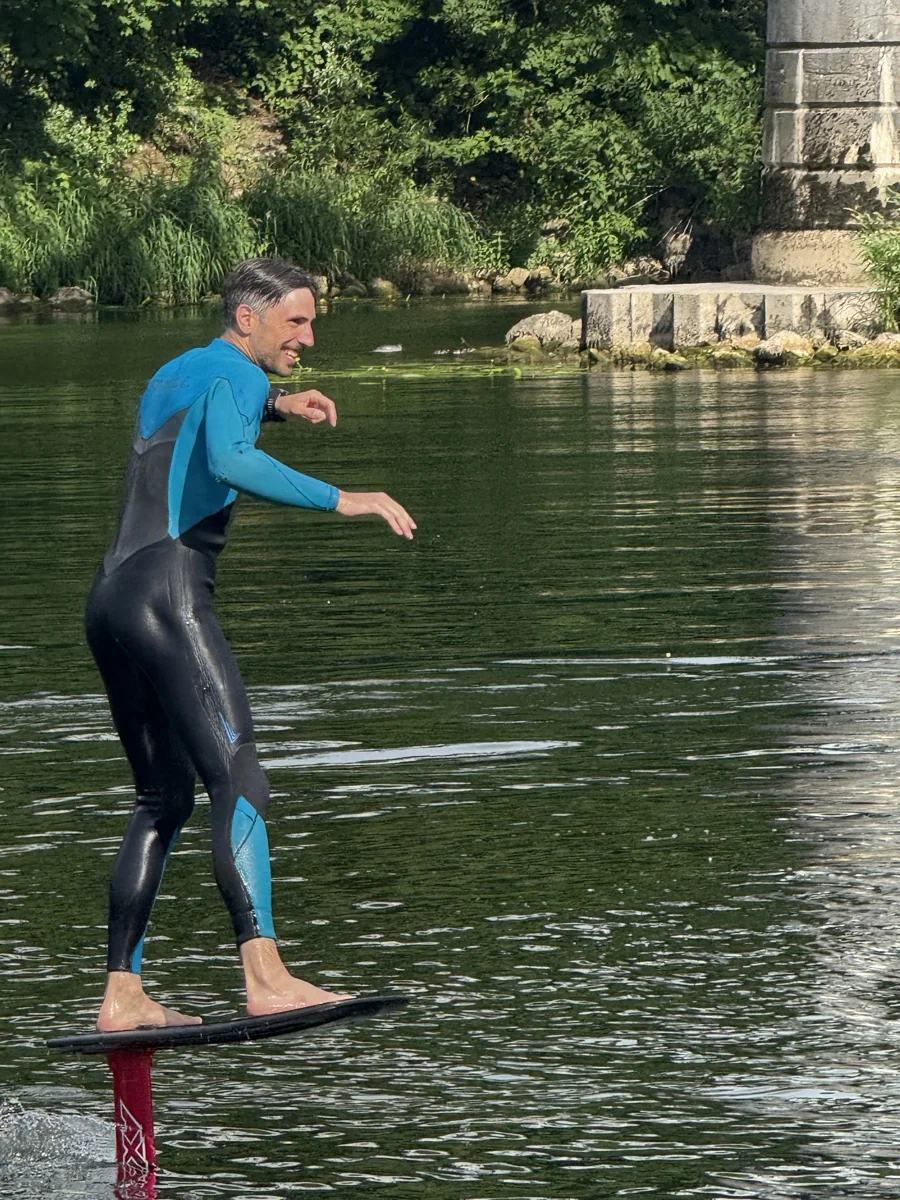 Une personne debout sur une planche surélevée au-dessus de la rivière par un foil