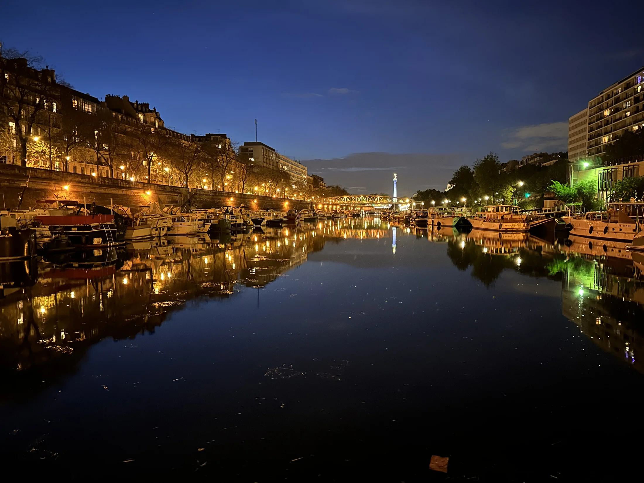 Lichten en boten weerspiegeld in het stille water van de Port de l’Arsenal bij nacht
