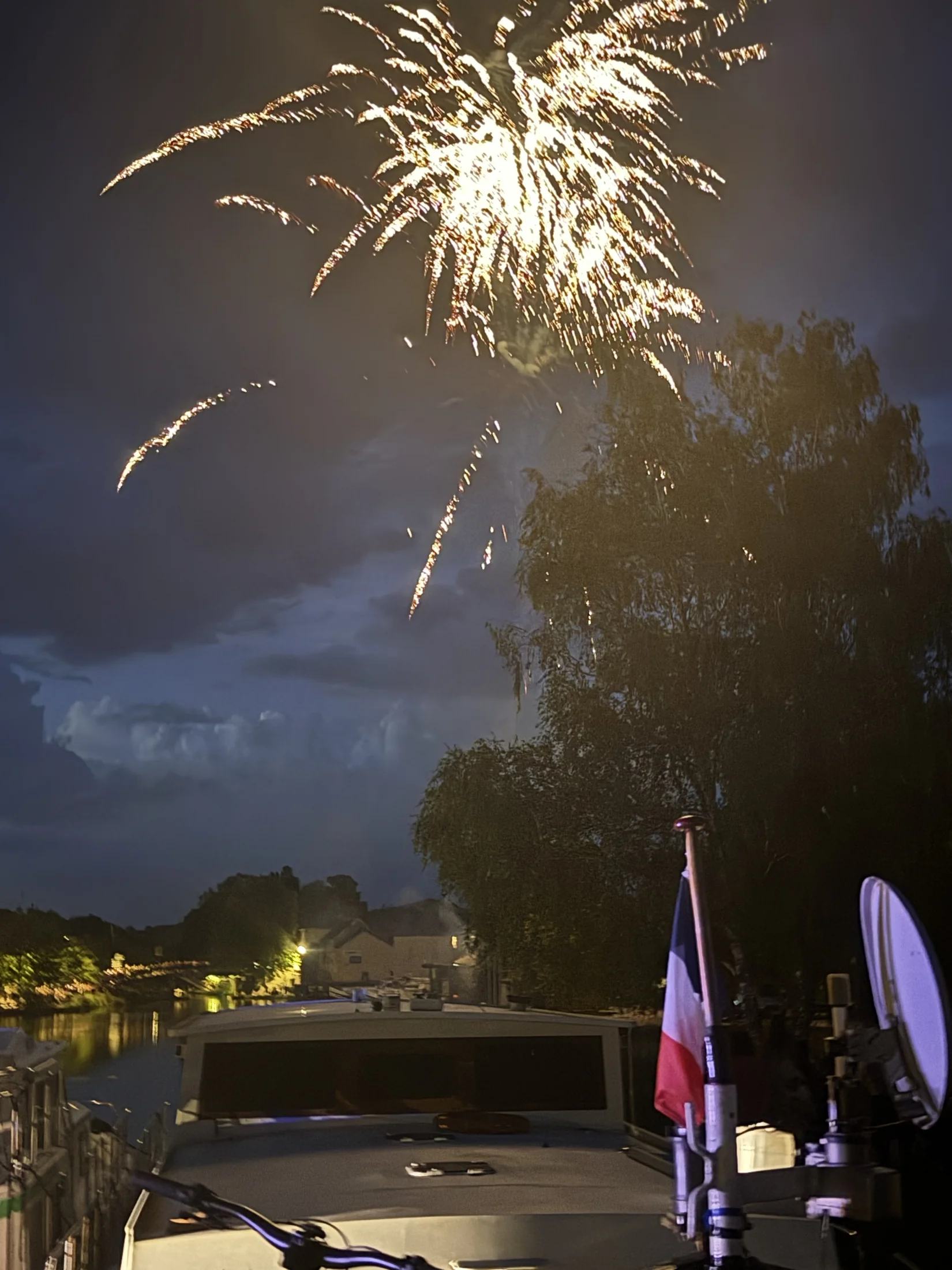 Vuurwerk boven de bomen, gezien over Maria’s dek