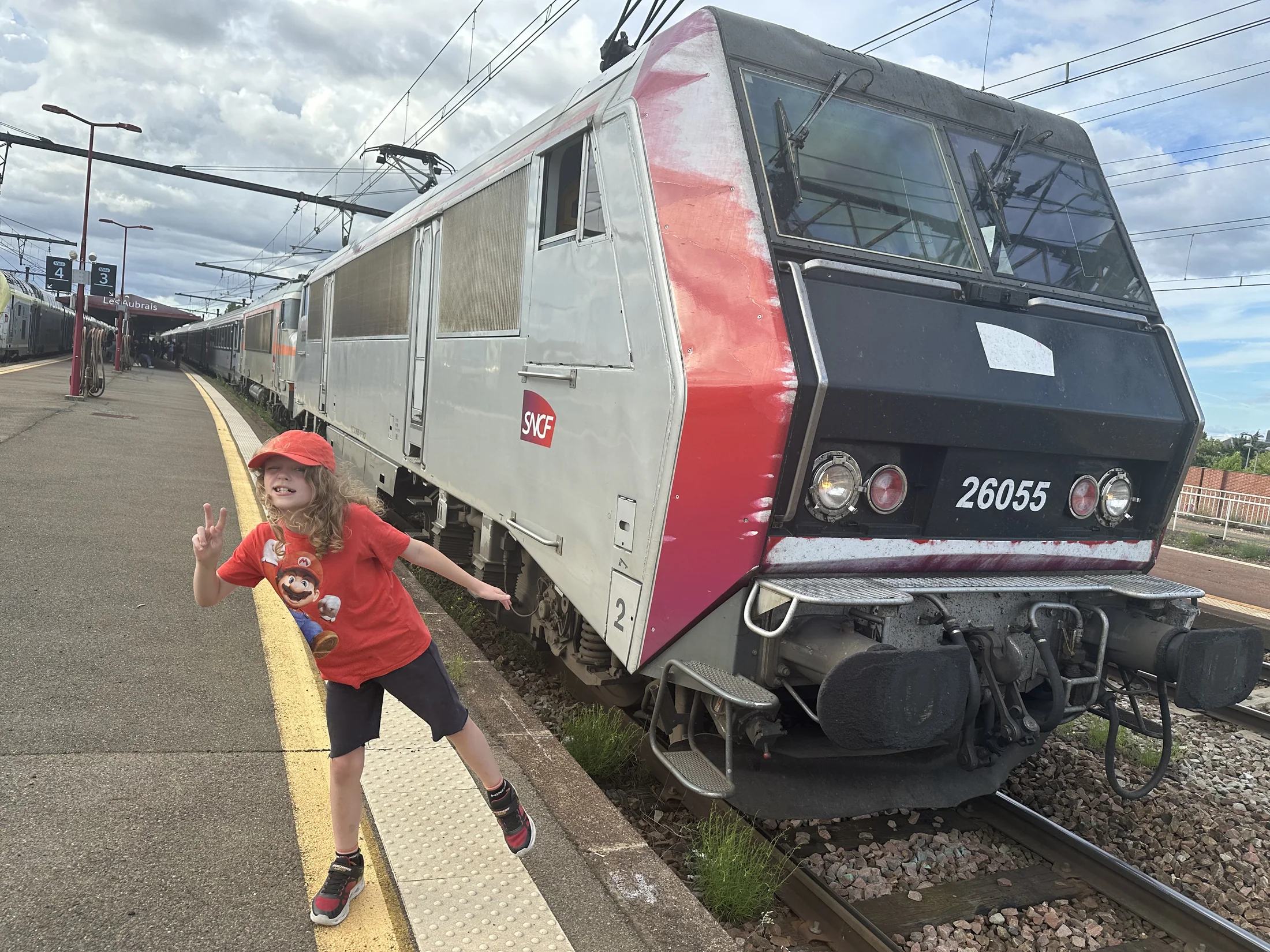 Harry naast een rode en grijze trein tijdens zijn reis naar Maria