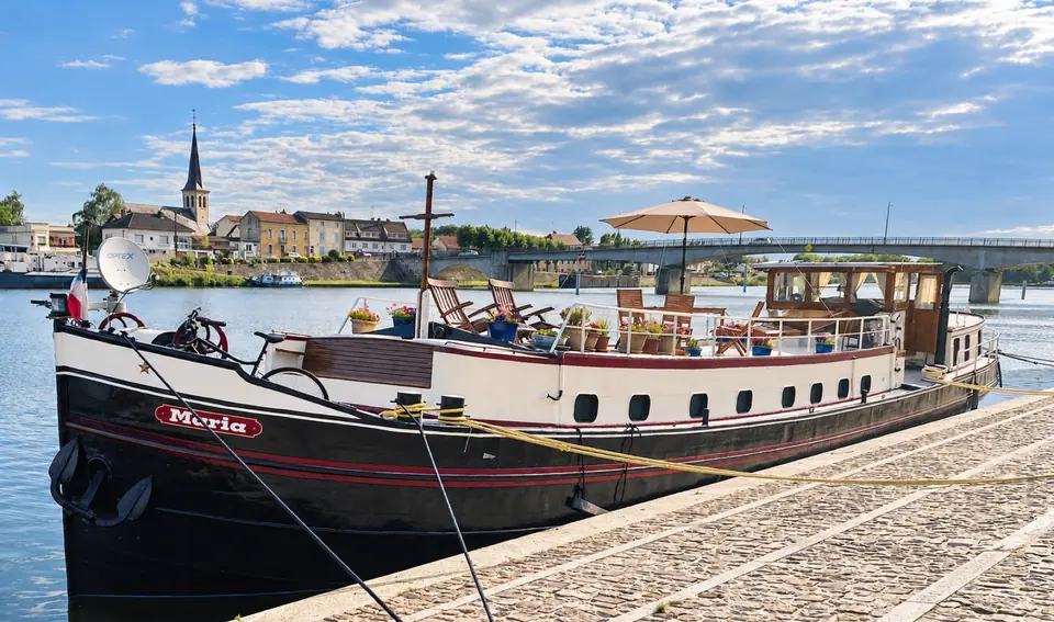 Maria de profil près d’une ville française, avec sa proue, son nom et la vie sur le pont visibles