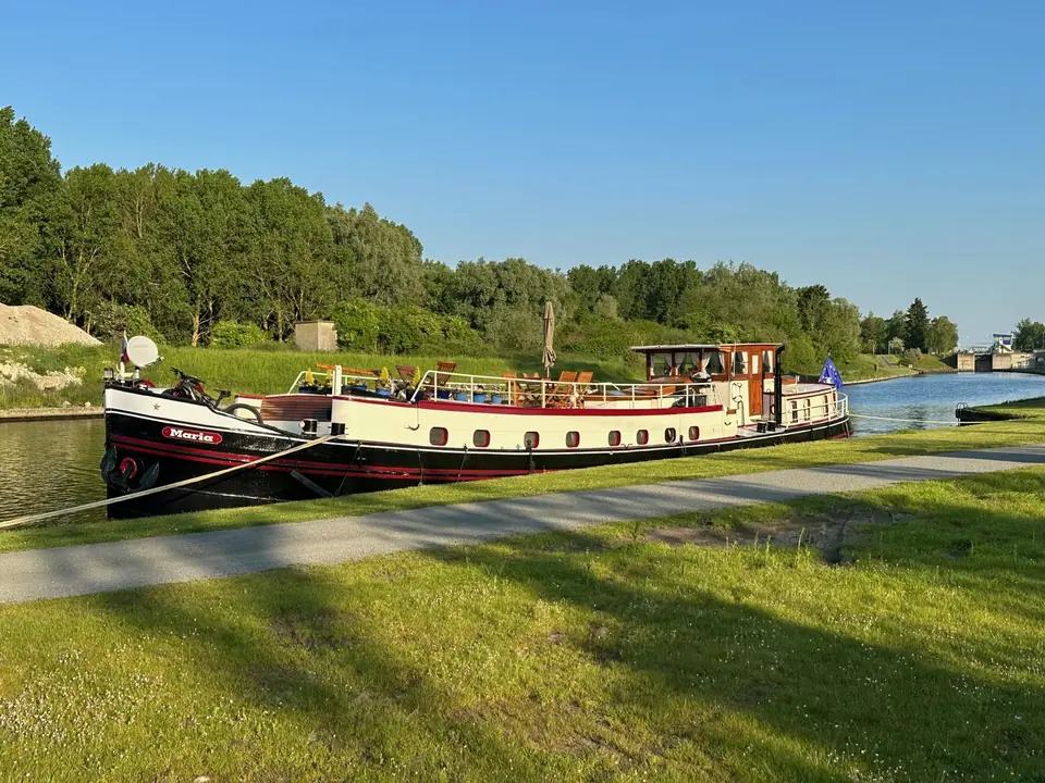 Maria amarrée près d’un chemin de halage herbeux, avec une écluse devant elle sur un canal paisible
