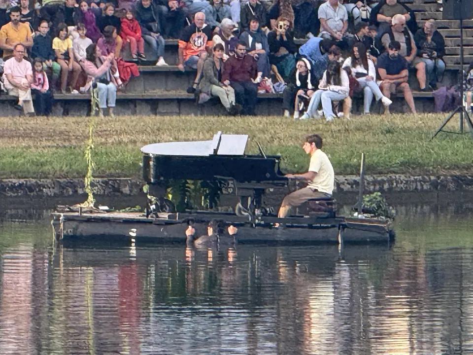 Un pianiste joue sur une scène flottante devant un large public à Génelard